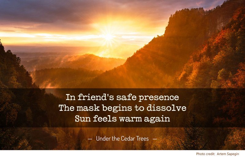 Photo of a sunset over forested mountains, with poem: In friend's safe presence / The mask begins to dissolve / Sun feels warm again — Under the Cedar Trees (Photo credit: Artem Sapegin)