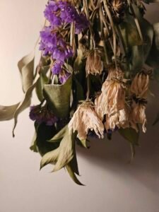 Close up photo of an upside-down dried bouquet of peach and purple flowers — the inspiration for the poem.